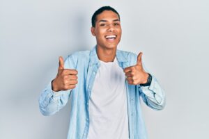 Young african american guy wearing casual clothes success sign doing positive gesture with hand, thumbs up smiling and happy. cheerful expression and winner gesture.